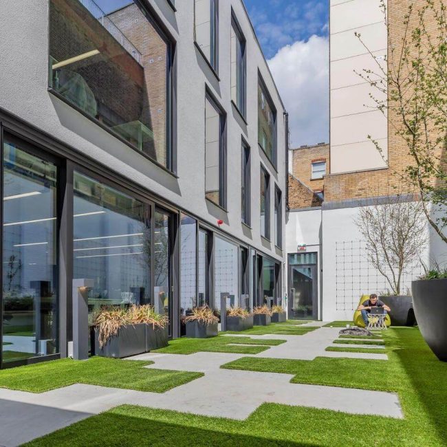 Folgate fora courtyard with man working on laptop